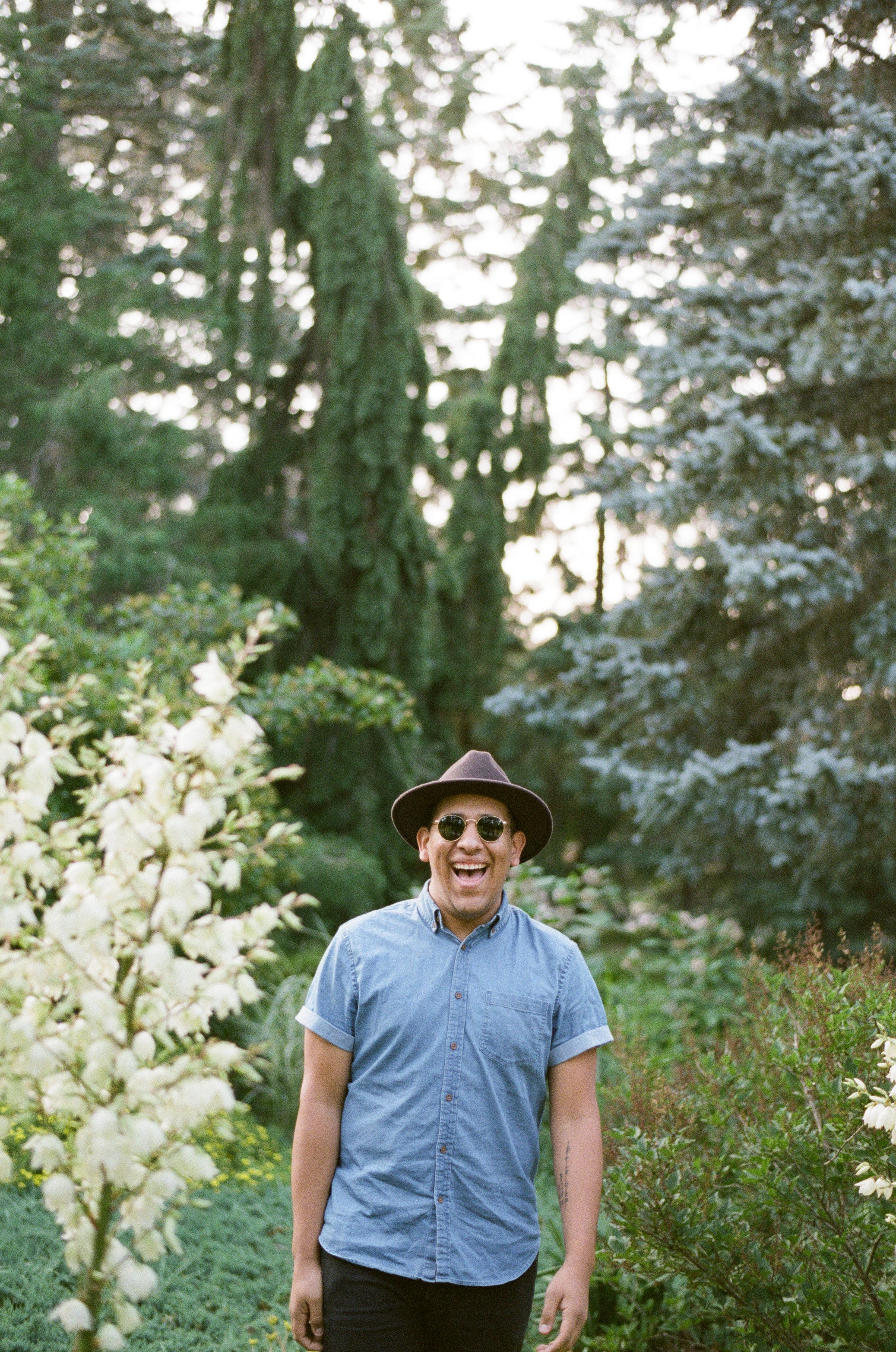 files/a-man-in-a-fedora-and-sunglasses-beams-in-the-woods.jpg
